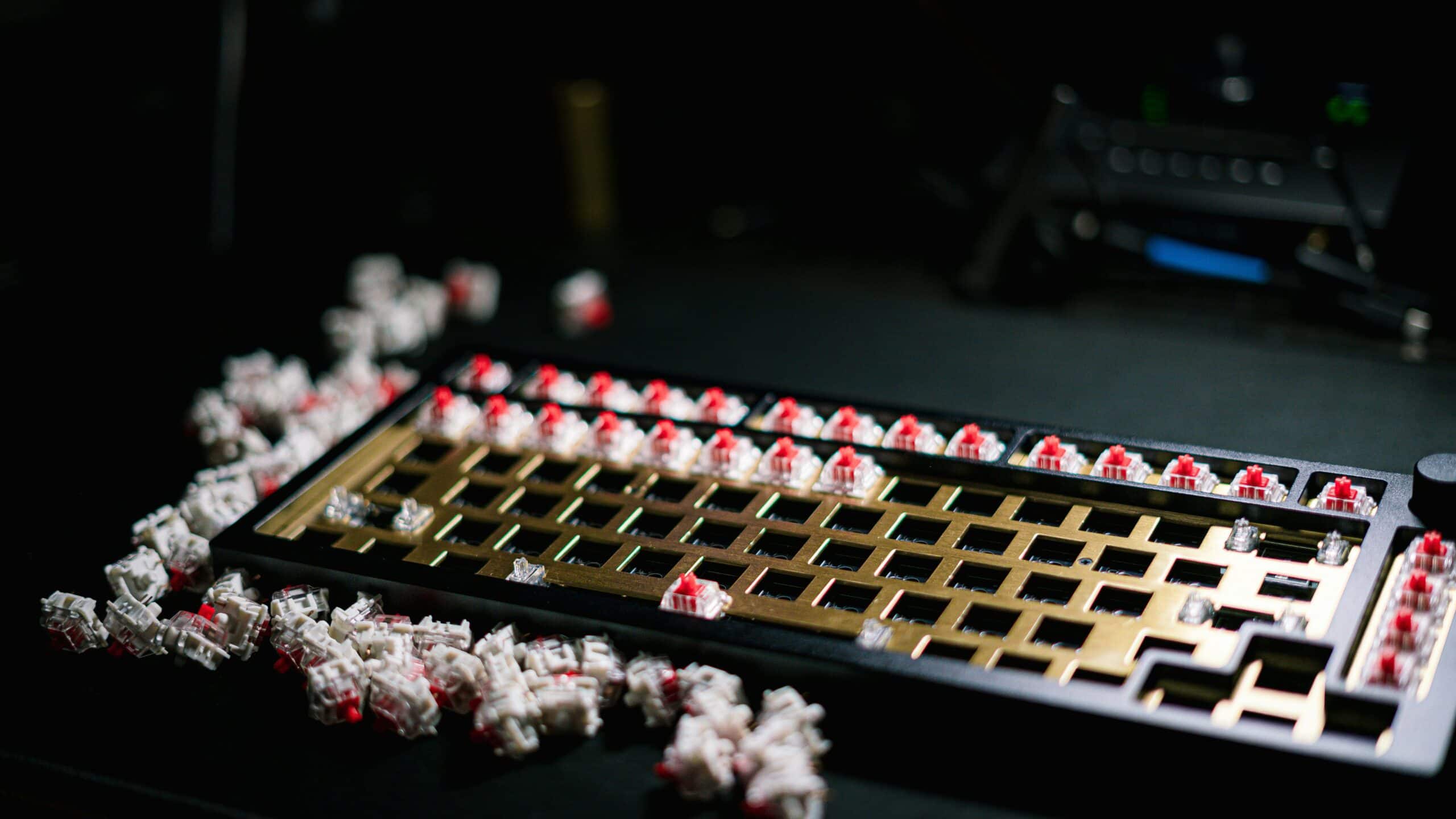 Mechanical keyboard switches being installed on a brass plate keyboard frame with red linear switches