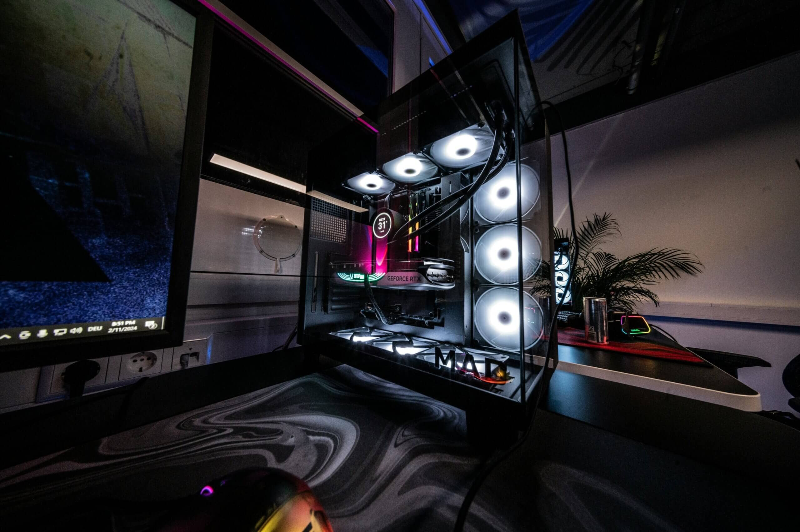 Open PC case showing a large AIO radiator with white-lit fans and an RGB-lit GPU on a desk, an enthusiast-tier setup that drives the aio vs air cooler conversation