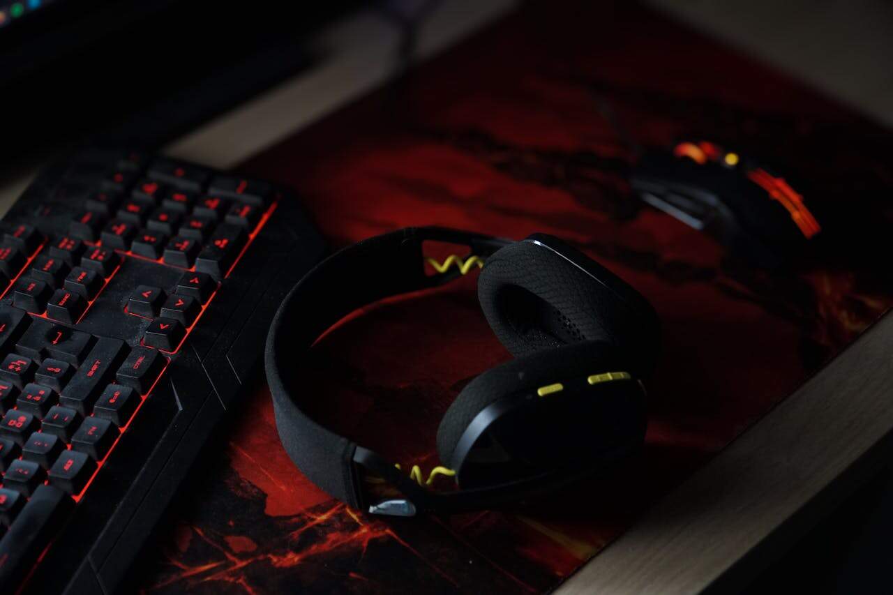 A sleek gaming setup featuring a backlit keyboard, wireless headphones, and a gaming mouse on a vibrant desk pad.