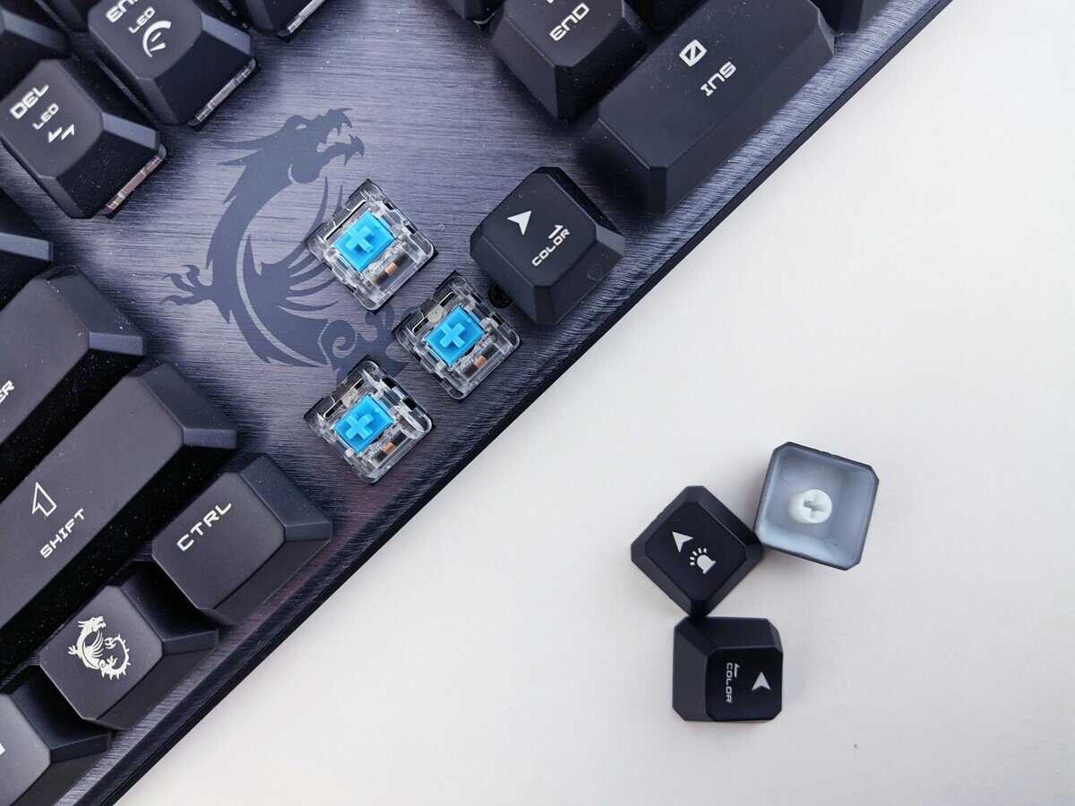 Close-up of blue best tactile switches installed in an MSI gaming keyboard with removed keycaps showing the switch housing and stem