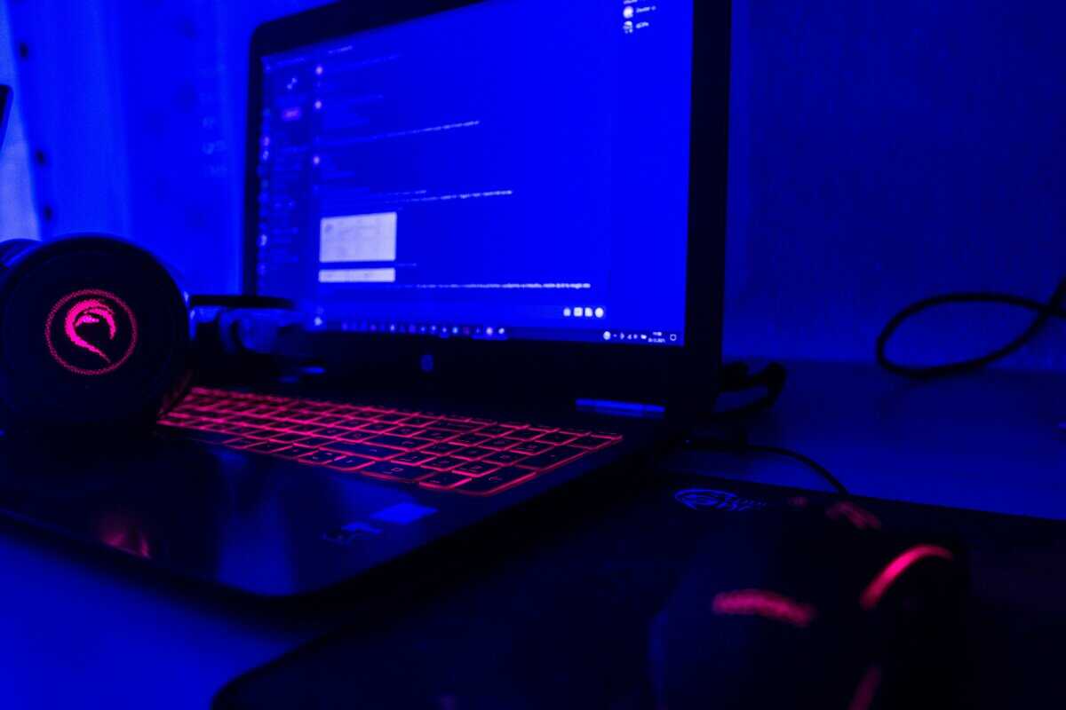 Best cheap laptop for gaming with red backlit keyboard, gaming headset, and RGB mouse in a blue-lit setup