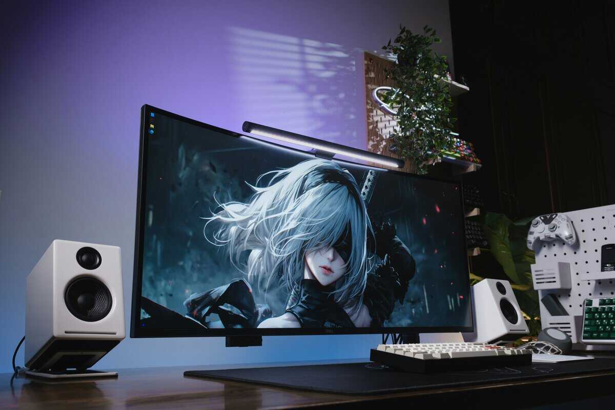 Best gaming monitor under $200 displayed in a desktop setup with white speakers, mechanical keyboard, and purple ambient lighting