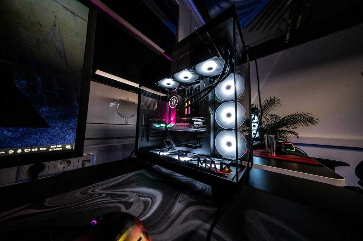 Gaming desktop PC with glass side panel showing white RGB fans and GeForce RTX GPU next to a monitor, representing the desktop side of the gaming laptop vs desktop debate