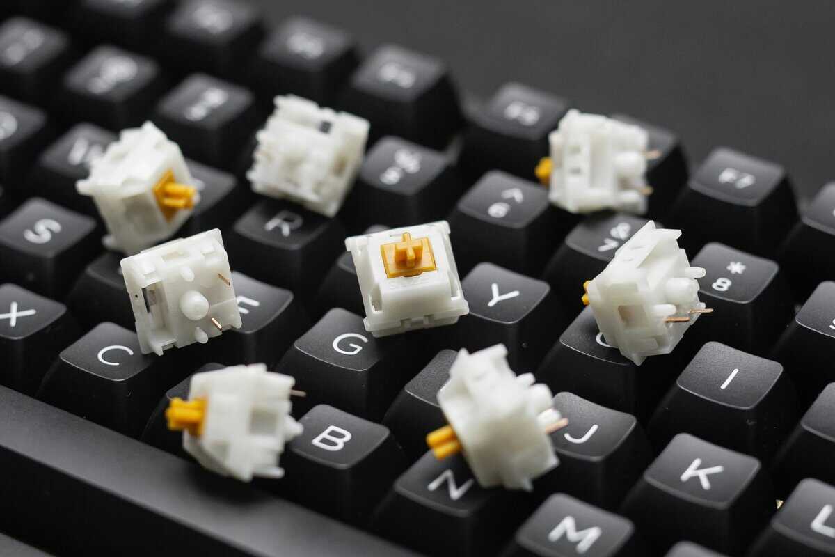 Best linear switches Gateron Milky Yellow switches with white housings and yellow stems resting on black mechanical keyboard keycaps