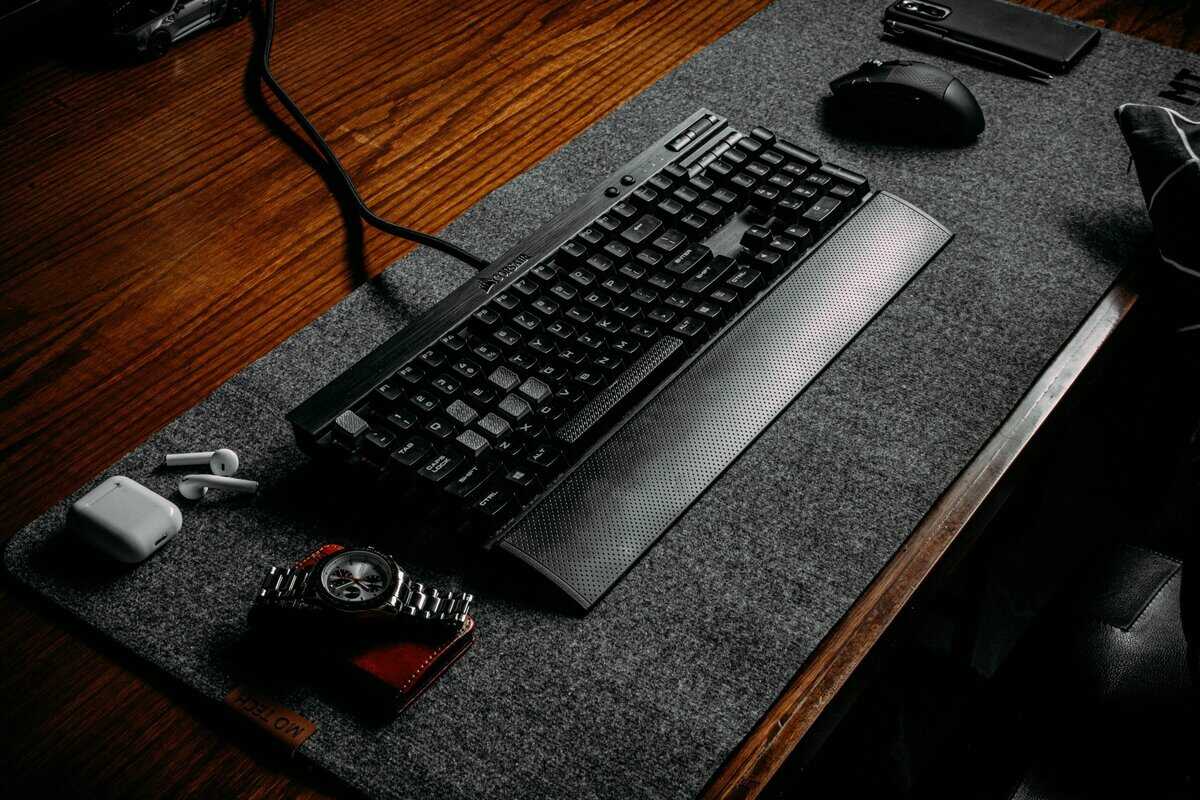 Corsair gaming keyboard with an integrated wrist rest for a keyboard on a felt desk mat, showing a built-in design