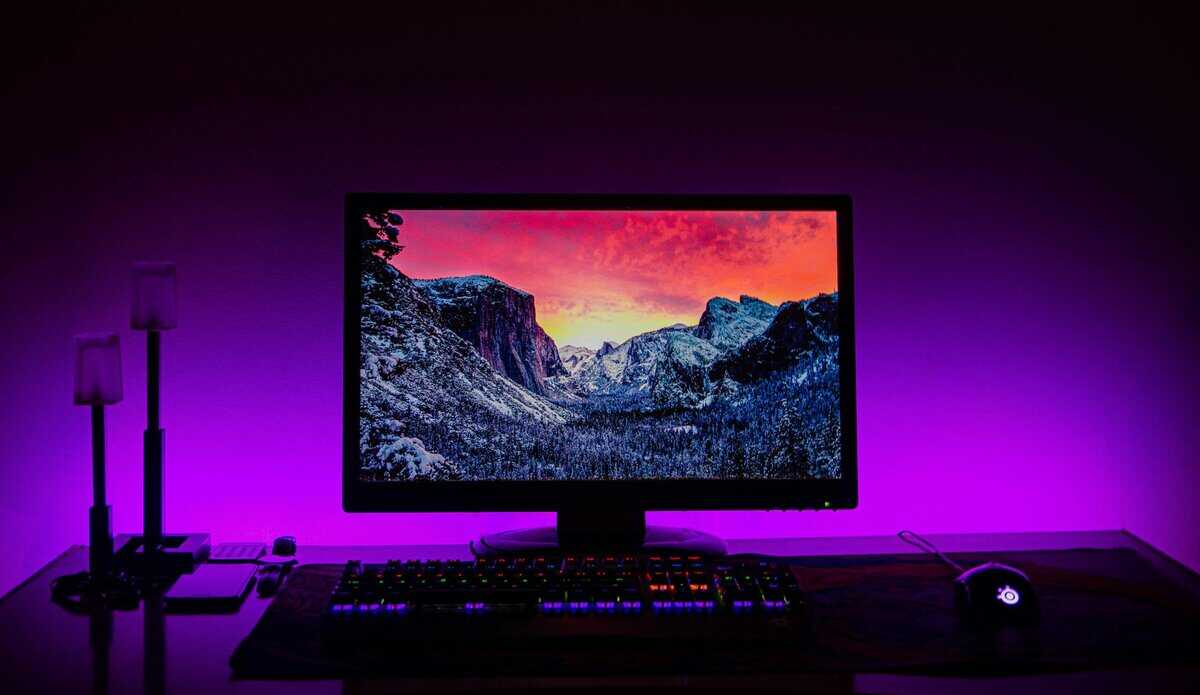 Best Asus monitor displayed on a gaming desk with purple RGB backlighting and mechanical keyboard