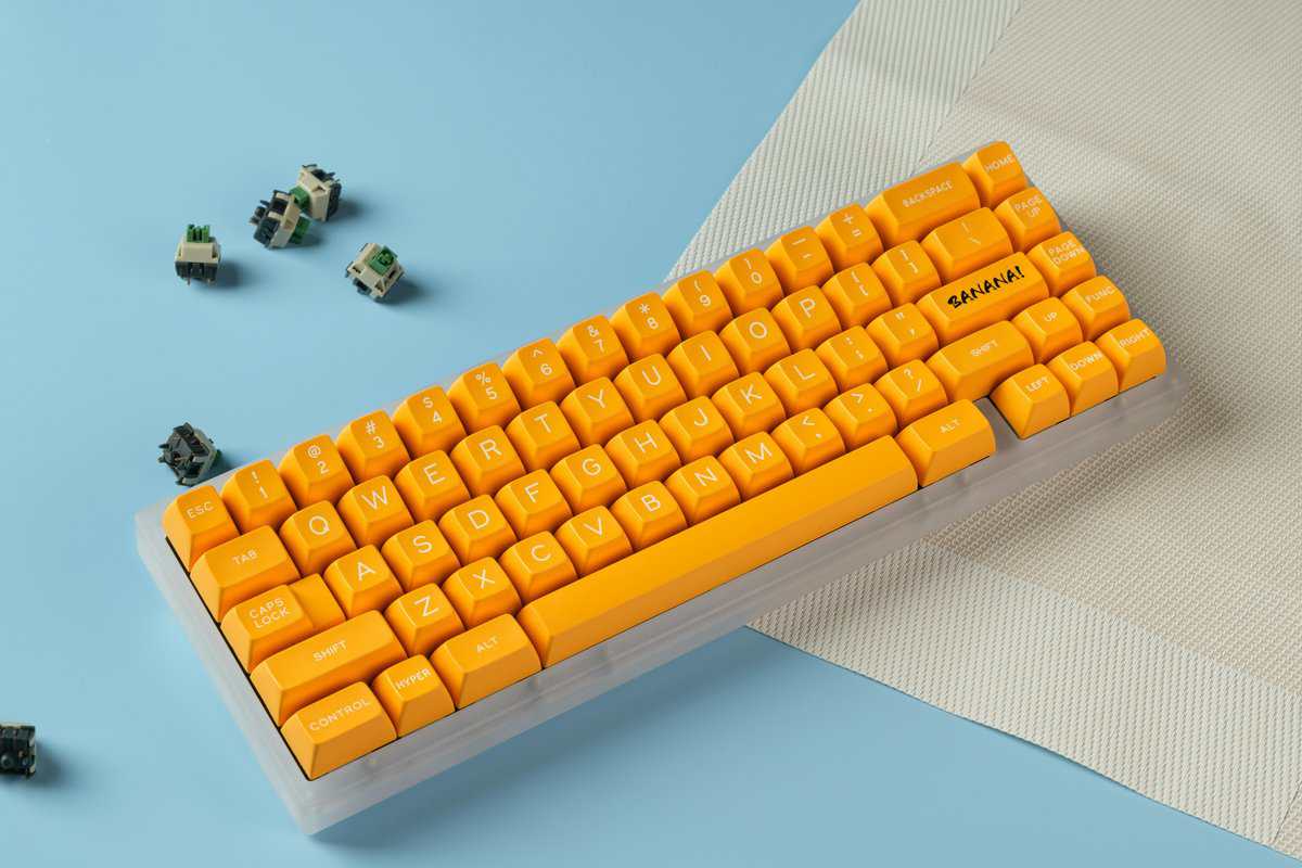 Custom 65% keyboard with yellow PBT keycaps and clear case, with hot-swappable mechanical switches removed nearby