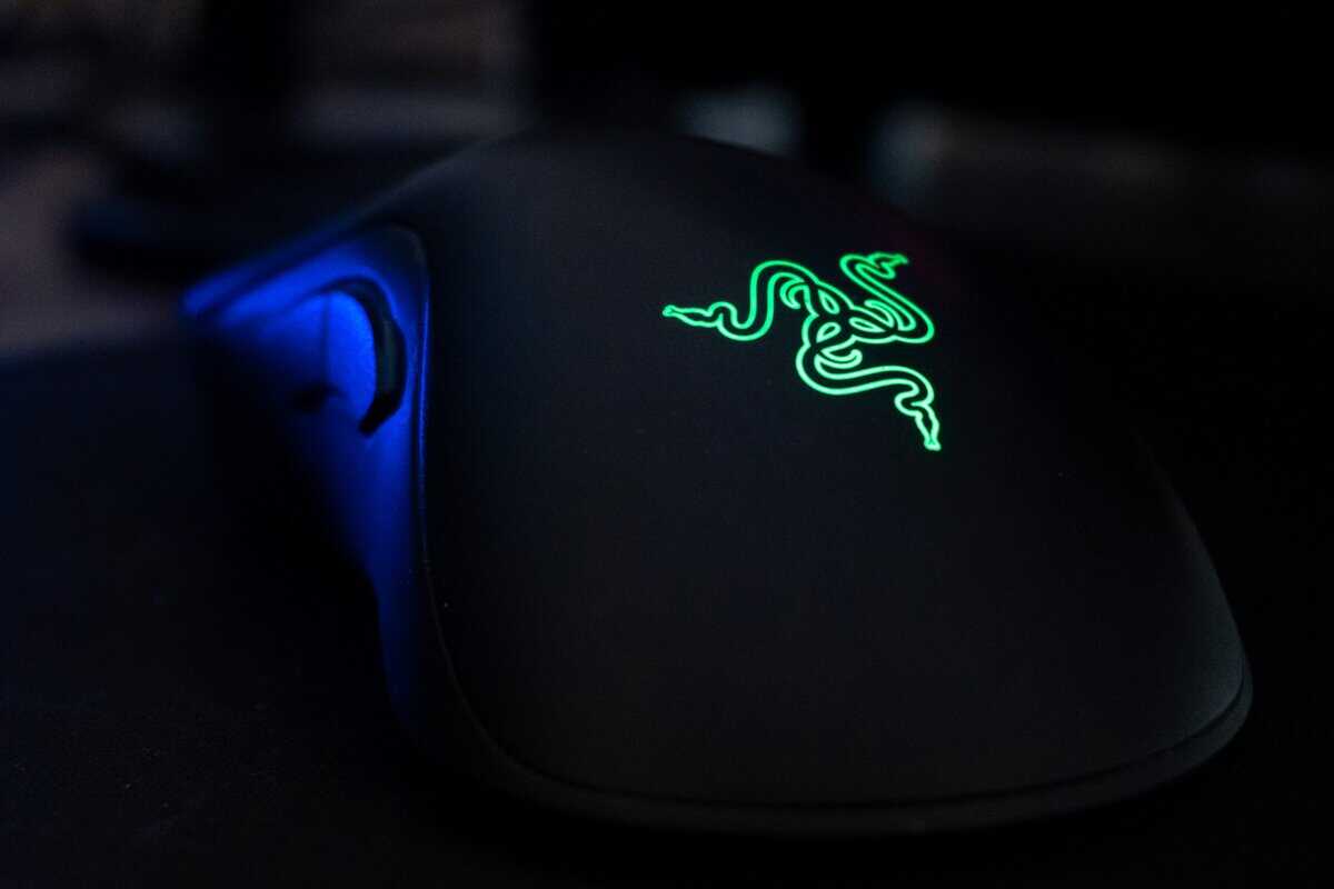 Black Razer gaming mouse with glowing green logo and blue side lighting highlighting the ergonomic shape of the best bluetooth mouse for long gaming sessions