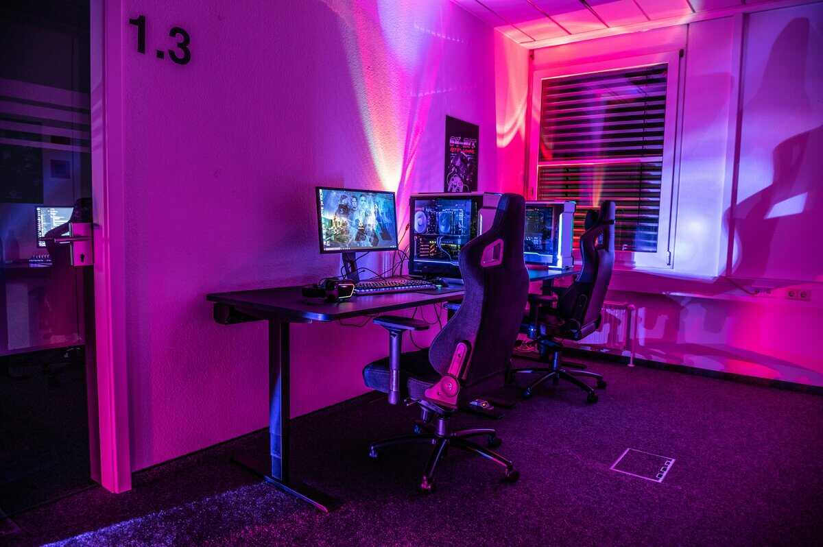 Dual streaming station with gaming PCs, monitors, and racing-style chairs in a room with pink RGB ambient lighting, configured with optimal OBS settings for streaming