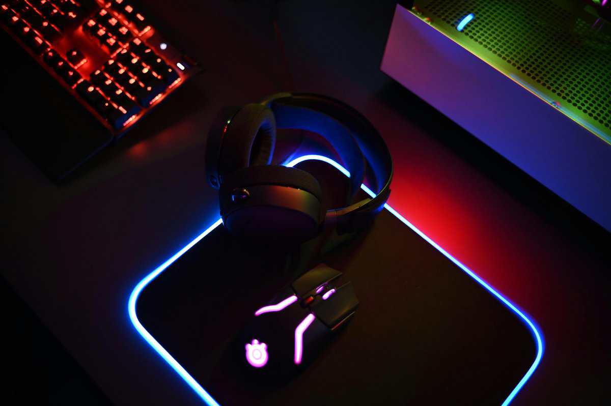 Gaming headset on RGB mousepad next to mechanical keyboard and PC — top gaming headsets setup