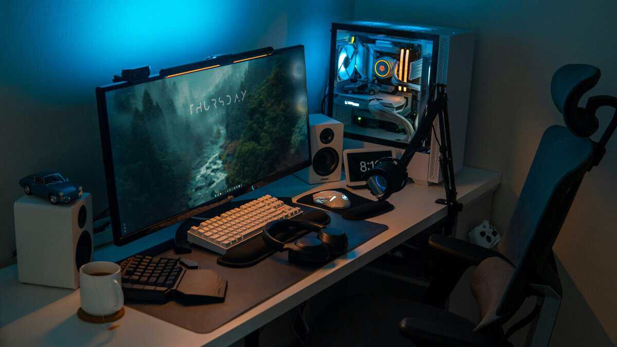 Compact gaming desk setup ideas with a single monitor, mechanical keyboard, desktop PC with glass side panel, and blue ambient lighting in a small room