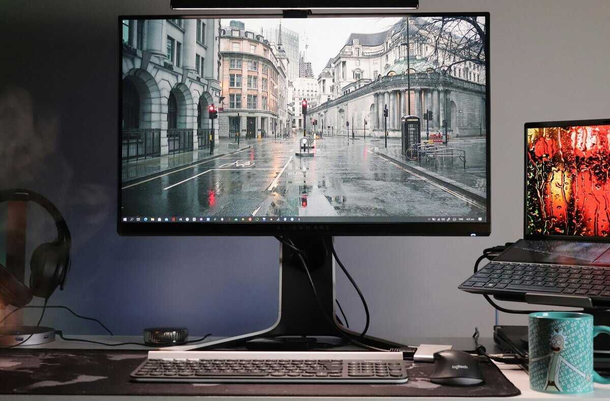 IPS gaming monitor on an adjustable stand with headphones and laptop nearby, showing the type of display in the 144hz vs 240hz debate