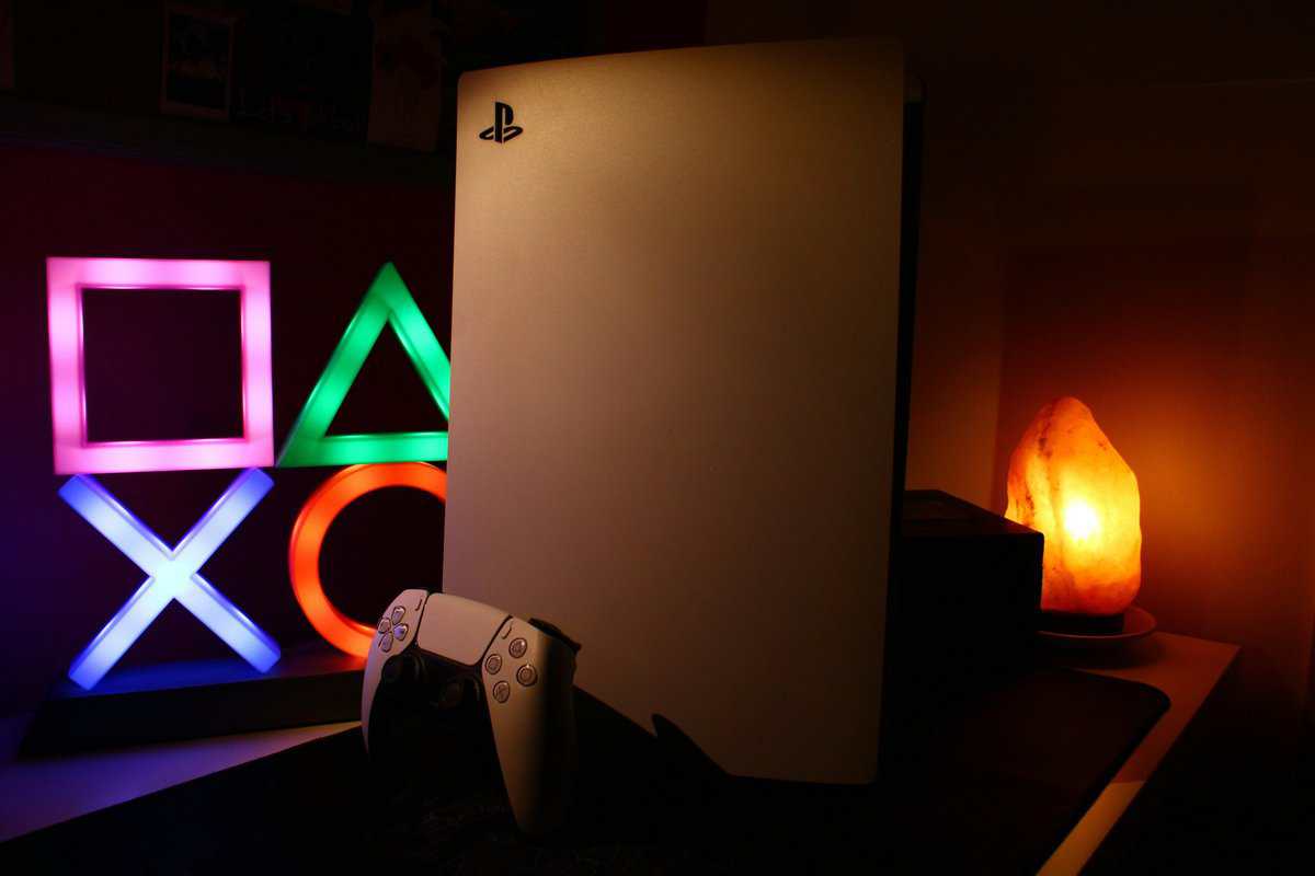 PS5 console with DualSense controller and glowing PlayStation button symbols on a shelf, the kind of setup that benefits from ps5 storage expansion
