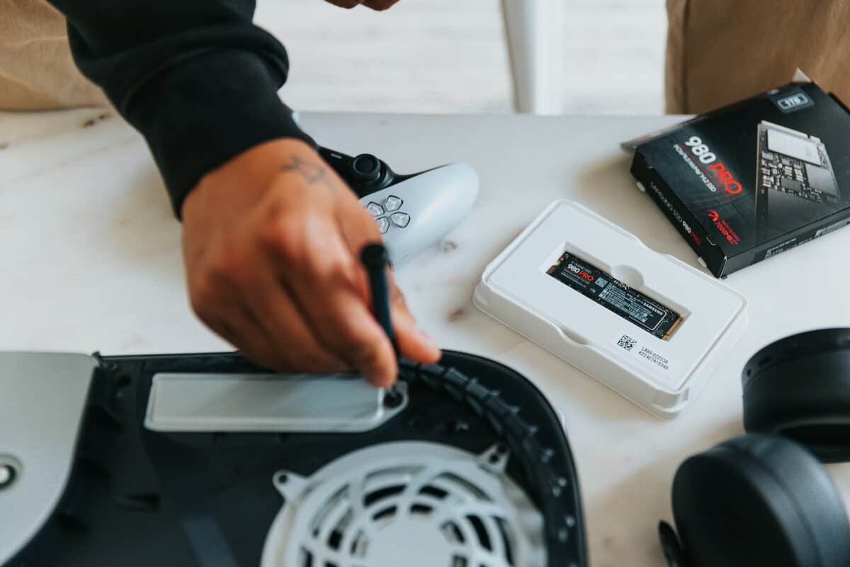 Hand using a screwdriver to install a Samsung 980 Pro M.2 SSD into an opened PS5 expansion bay, showing ps5 storage expansion in action