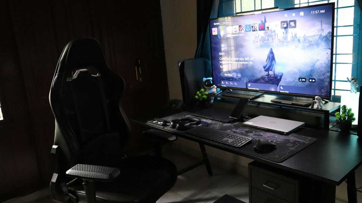 Black gaming chair next to a desk with a monitor showing Hogwarts Legacy, a typical setup featuring the best budget gaming chair