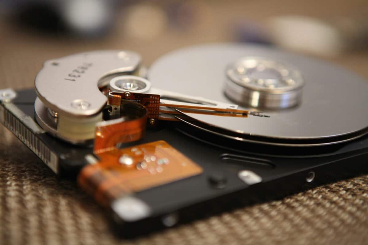 Close-up of an open hard disk drive showing the spinning platter and read arm, the traditional HDD side of the ssd vs hdd for gaming debate