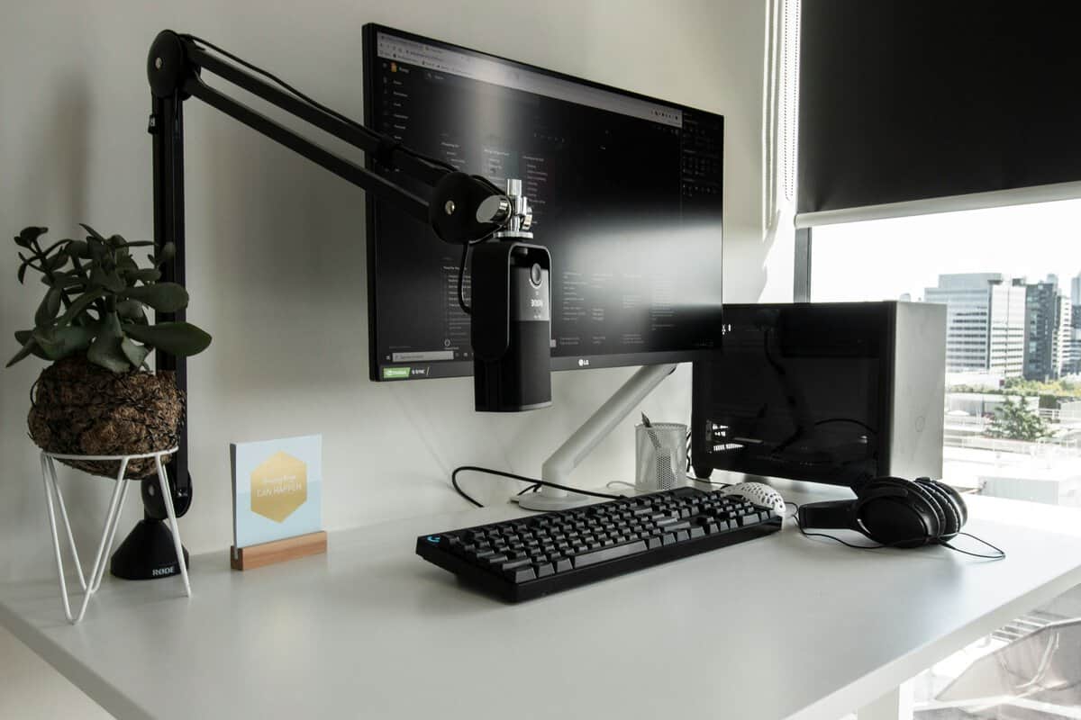 Rode boom arm and microphone behind a monitor on a clean desk, a clear example of the best microphone boom arm in a streaming setup
