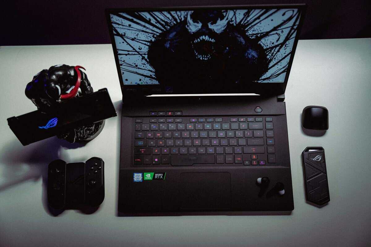 ASUS ROG gaming laptop on a desk with controller and earbuds, representing the best gaming laptop under $1500 for a complete setup