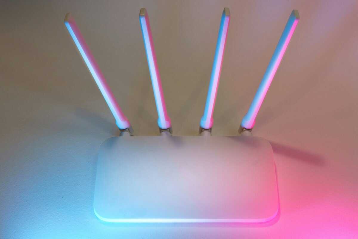White Wi-Fi router with four antennas and pink-blue RGB lighting, representing the best gaming router options for 2026