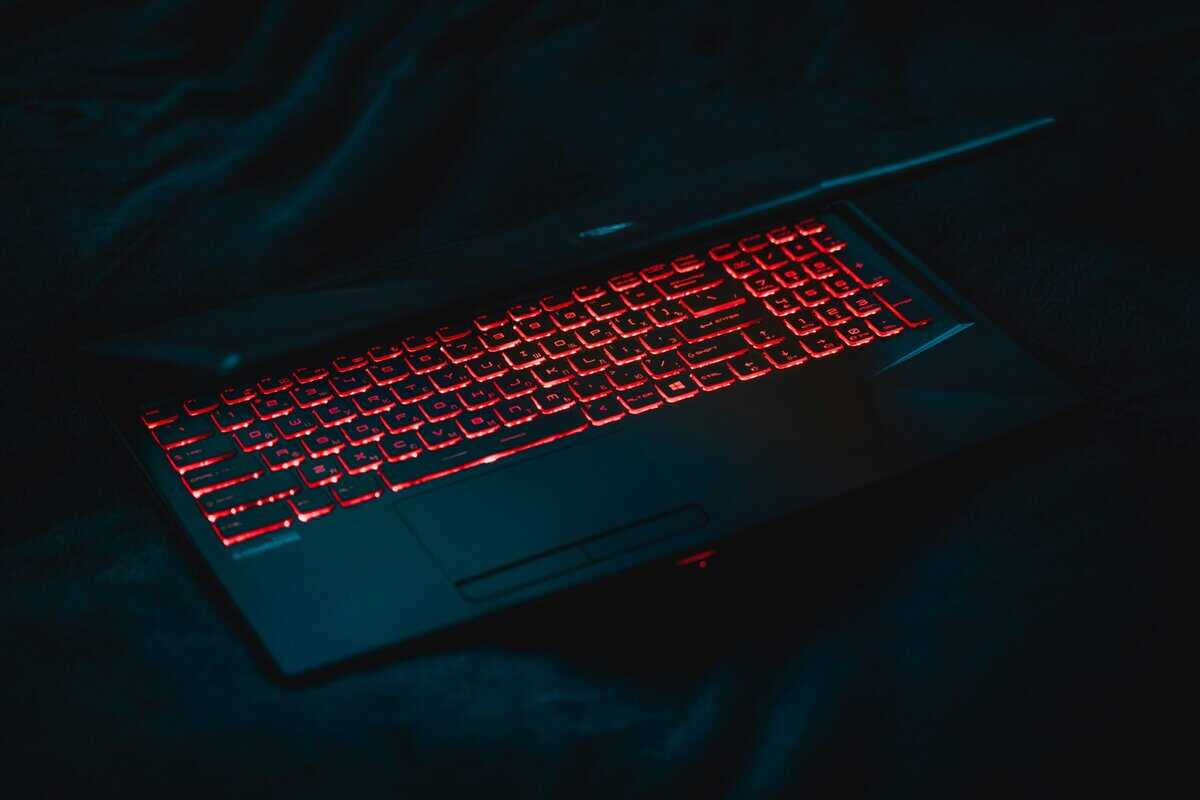 Gaming laptop with red backlit keyboard in a dark room, showcasing the portable appeal of the best gaming laptop under $1500