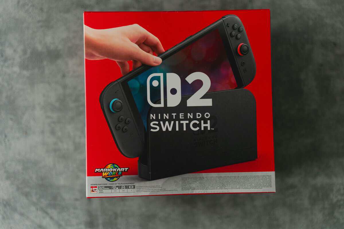Nintendo Switch 2 dock sitting on a desk beside a TV setup — the central piece for proper docked play
