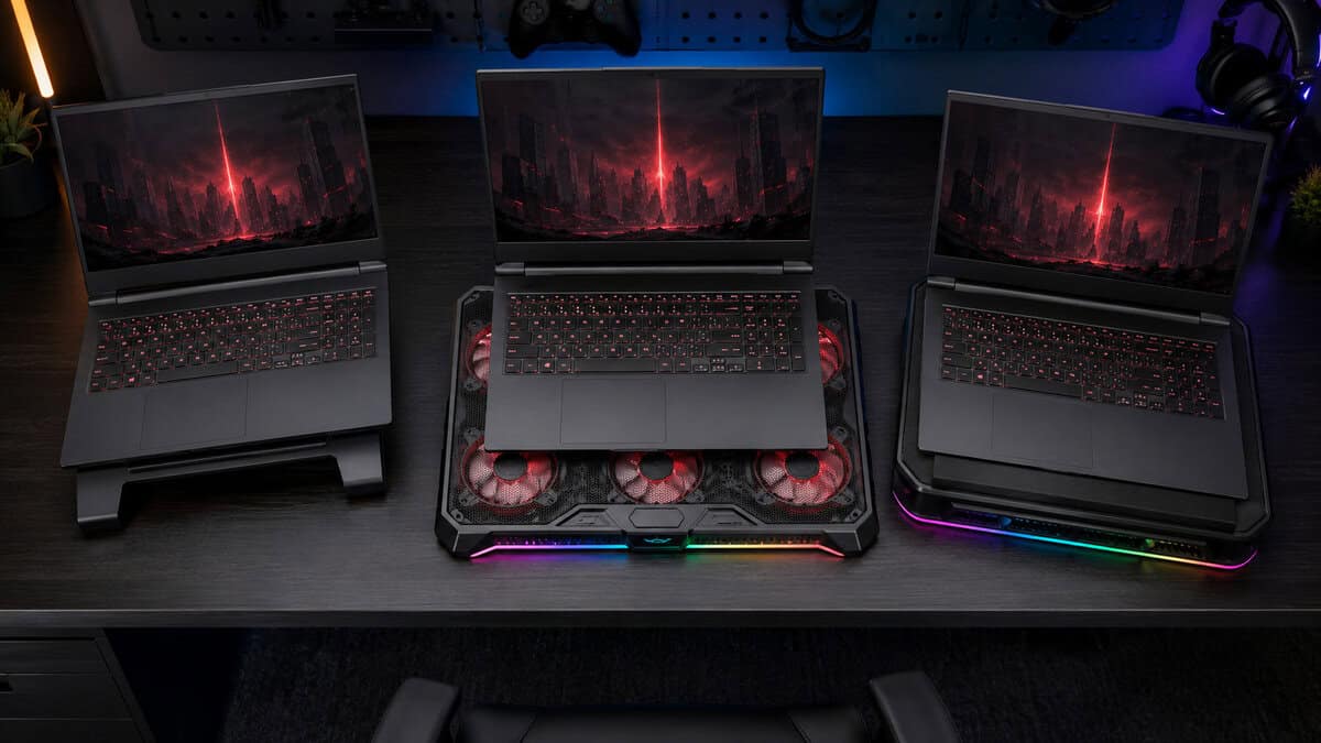 Three gaming laptops compared side by side on a passive riser stand and two RGB fan pads, illustrating the design choices behind the best laptop cooling pad