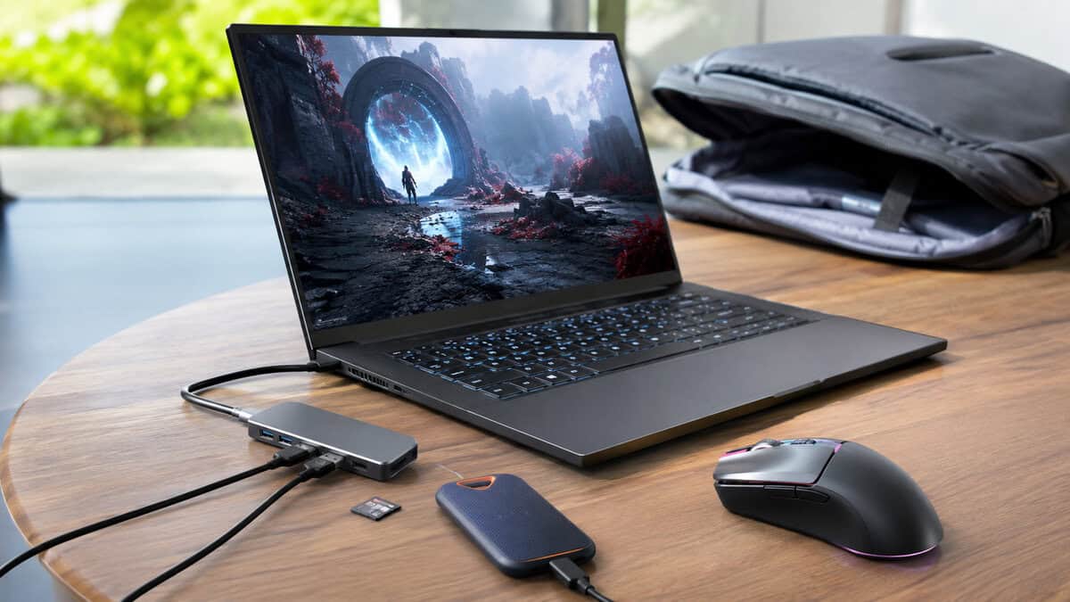 Compact hub with an SD card and portable SSD beside a gaming laptop and travel bag, the best usb c hub working as a portable desk