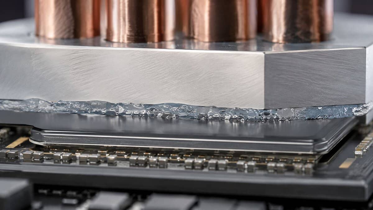 Macro view of the best thermal paste squeezing out between a copper cooler cold plate and the CPU heat spreader