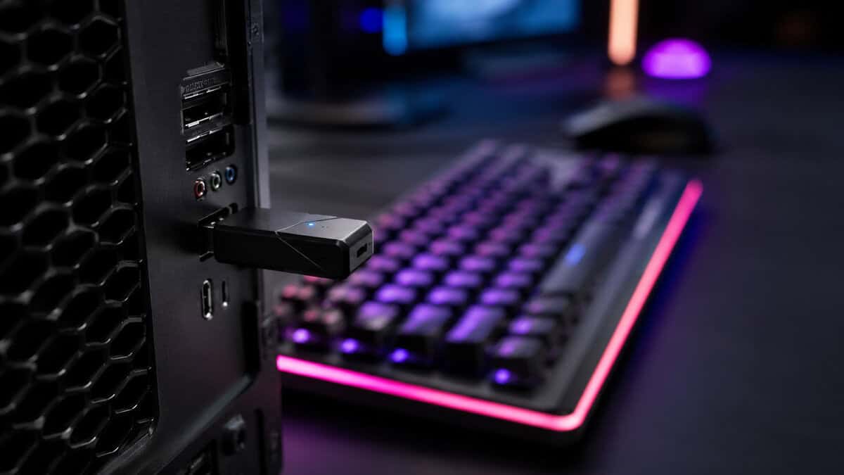 Compact bluetooth adapter for PC use plugged into the rear panel beside a color-lit mechanical keyboard