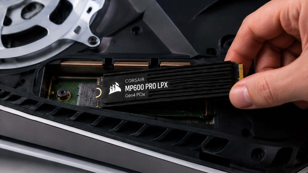 Hand lowering the Corsair MP600 Pro LPX into an open PS5 expansion slot, installing the best ssd for ps5 heatsink-first