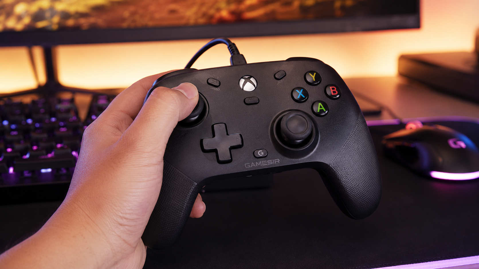 Hand holding a black GameSir wired gamepad over an RGB desk, the pad that leads any best hall effect controller shortlist