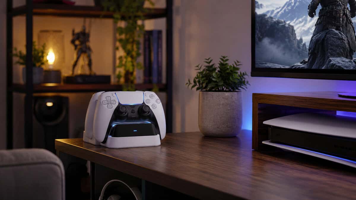 PS5 controller charging station holding a docked DualSense on a living room side table beside the TV and console