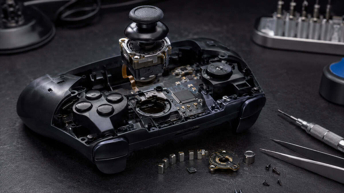 Disassembled controller with its joystick module lifted out beside tiny magnets and precision tools, the hardware at the heart of tmr vs hall effect