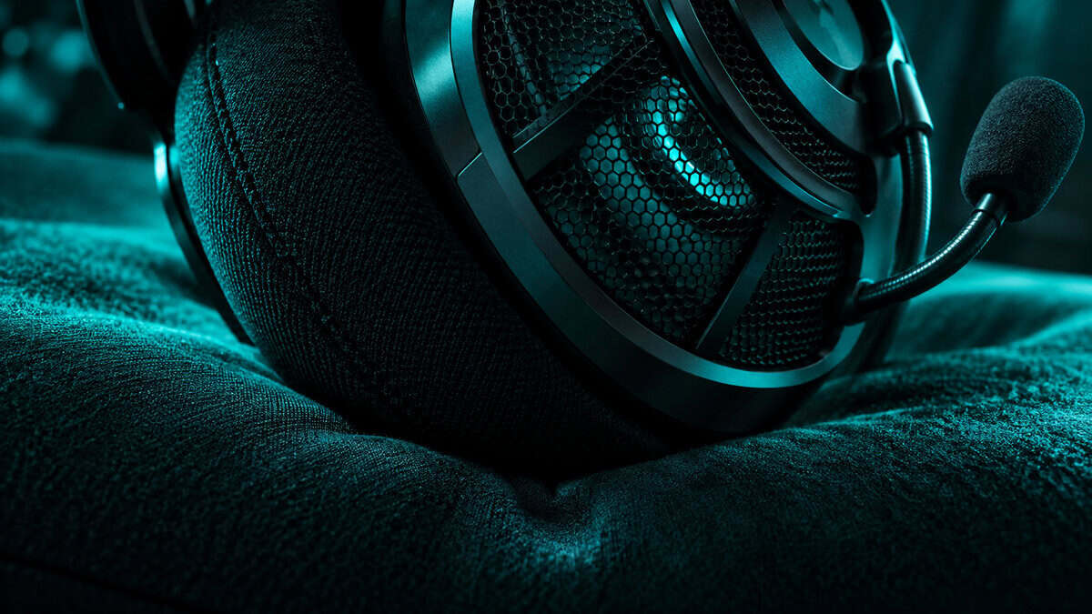 Macro close-up of a headset ear cup grille and memory foam cushion with a boom mic under teal light, the seal and driver that decide imaging in the best headset for CS2