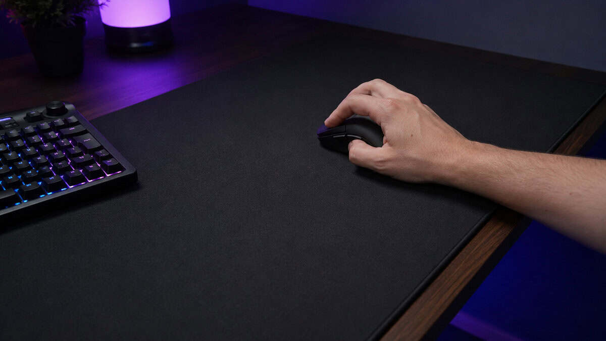 Claw grip on a compact mouse at the edge of a large cloth pad, testing fit before picking the best mouse for Wardogs