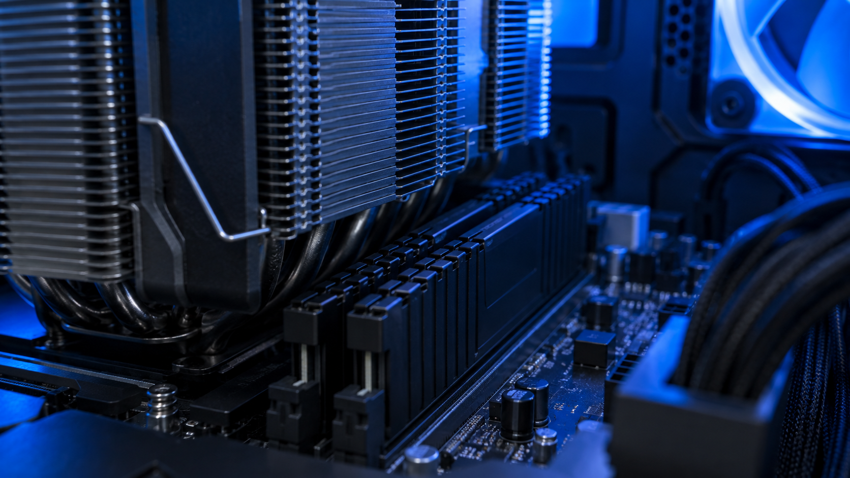 Close view inside a blue-lit PC showing low-profile black memory sticks seated under a wide dual-tower air cooler, the clearance check that matters when fitting the best DDR4 RAM