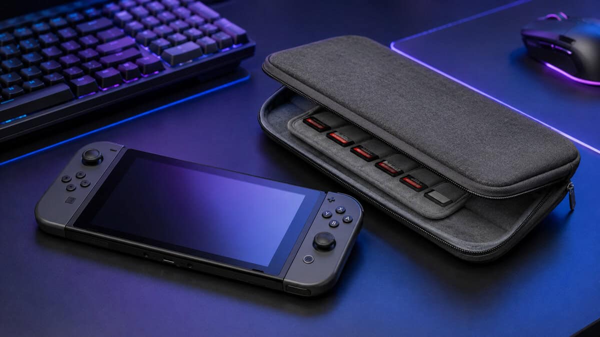 Slim gray switch 2 case half-open on an RGB gaming desk showing interior game card slots beside the handheld console