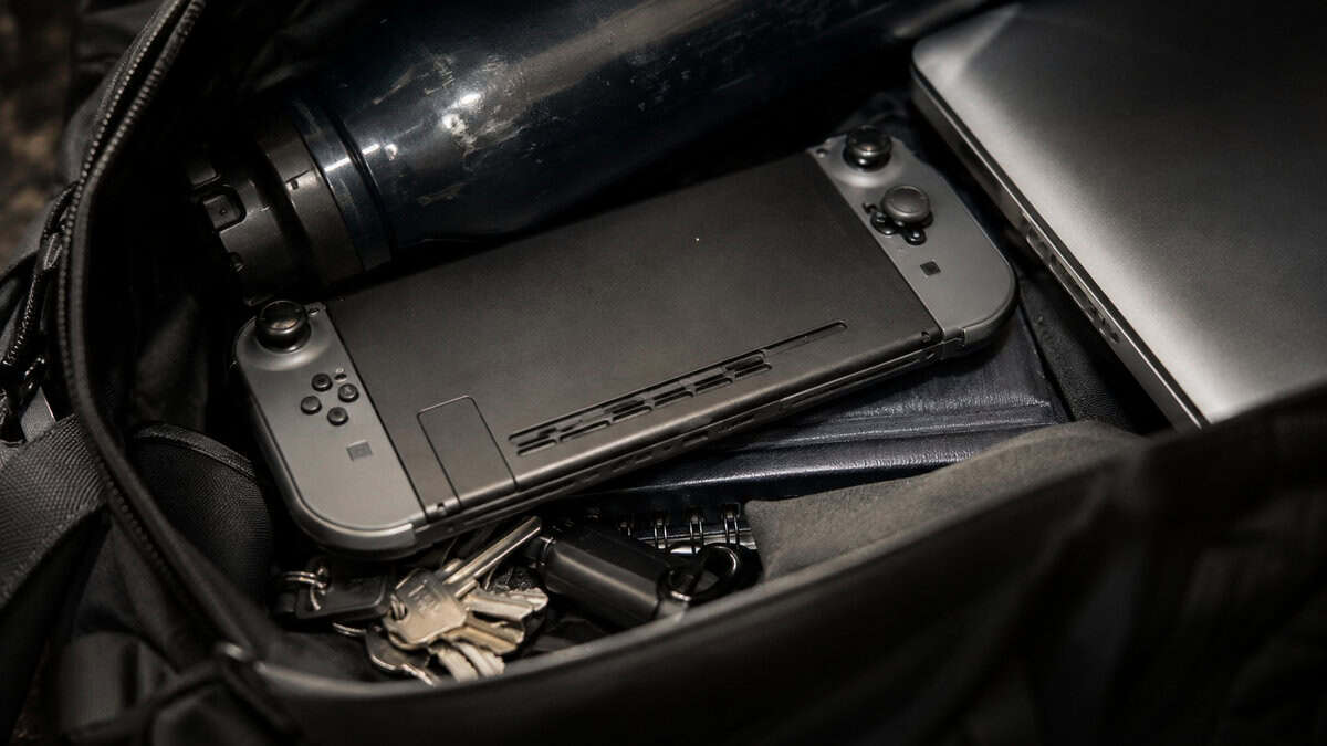 Handheld console riding unprotected in a backpack with keys and a water bottle, the problem a switch 2 case exists to solve