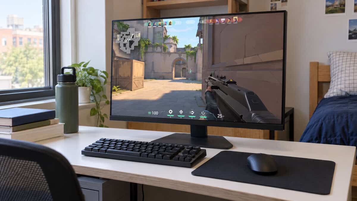 24-inch monitor on a white dorm desk beside a sunny window with a tactical shooter on screen, a compact daytime setup for weighing 1080p vs 1440p at a smaller screen size