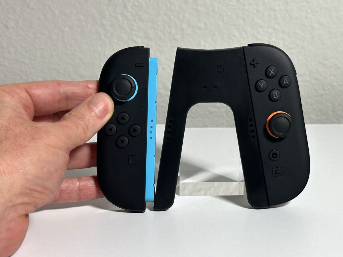 Hand snapping a Joy-Con 2 with a blue rail onto the magnetic side of the JSAUX Switch 2 charging grip