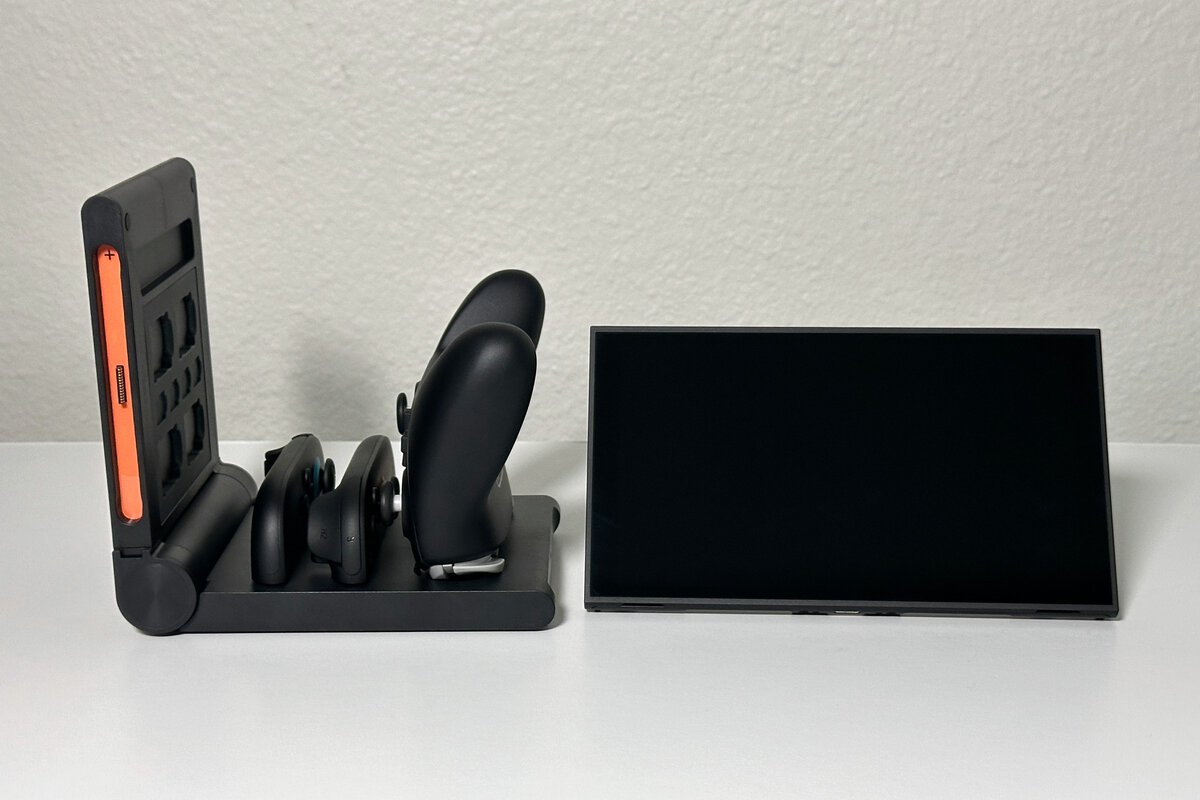 JSAUX switch 2 pro controller charging dock loaded with controllers next to a Nintendo Switch 2 console on a white desk