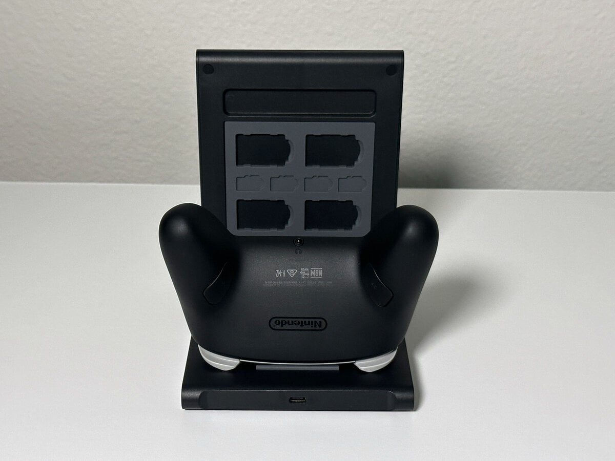 Pro Controller seated on the JSAUX switch 2 pro controller charging dock, seen from behind with the game card panel above it