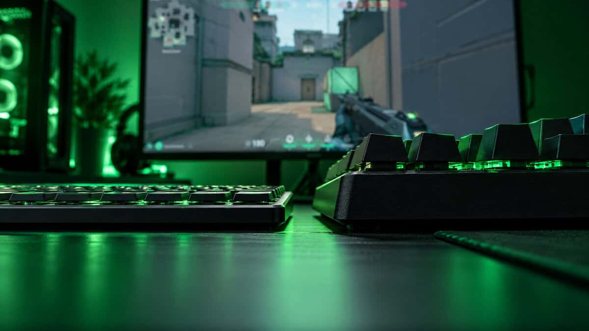 Side-on view of a thin low-profile mechanical keyboard next to a much taller standard mechanical keyboard under green light